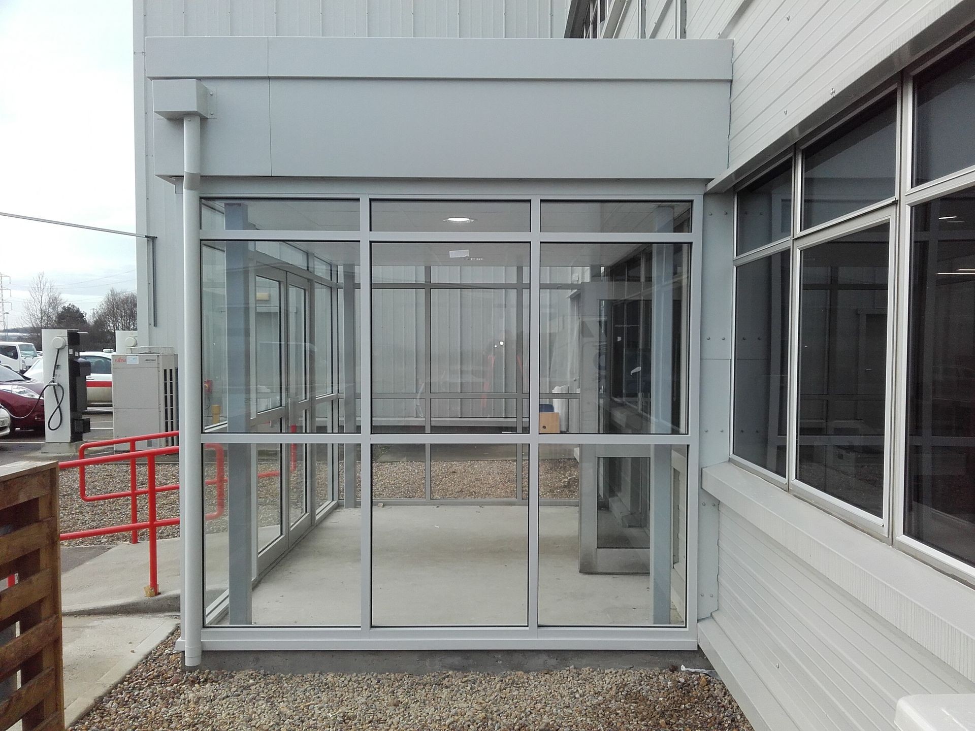 Glass-enclosed entrance vestibule of a commercial building with gray metal framing and clear glass panels.